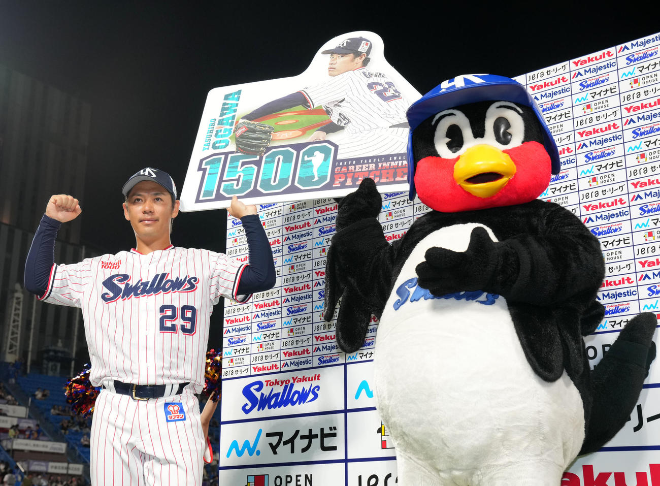 ヤクルト対DeNA 1500投球回達成ボードを掲げるヤクルト小川。右はつば九郎（撮影・横山健太）