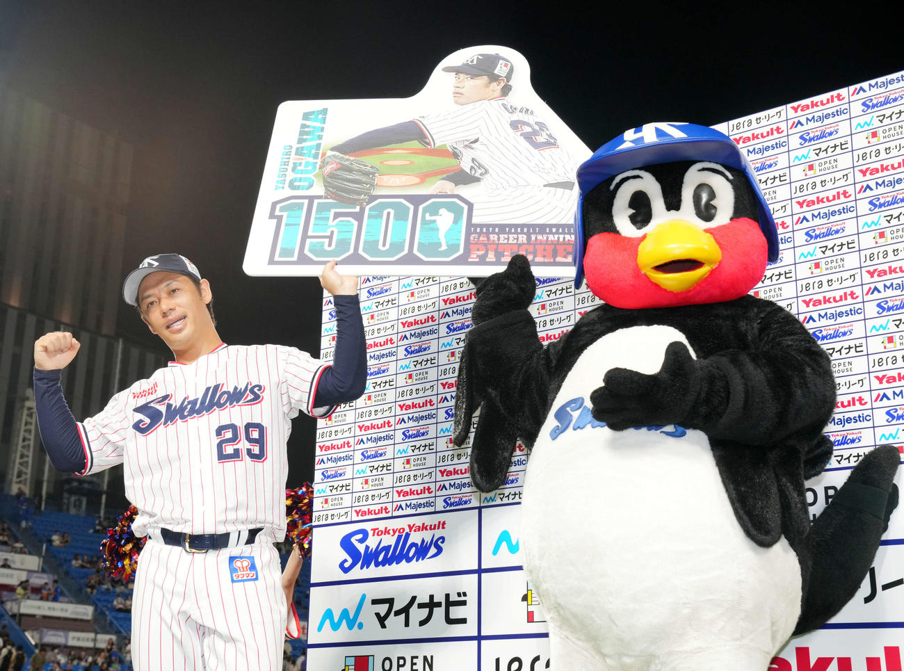 ヤクルト対DeNA 1500投球回達成ボードを掲げるヤクルト小川。右はつば九郎（撮影・横山健太）