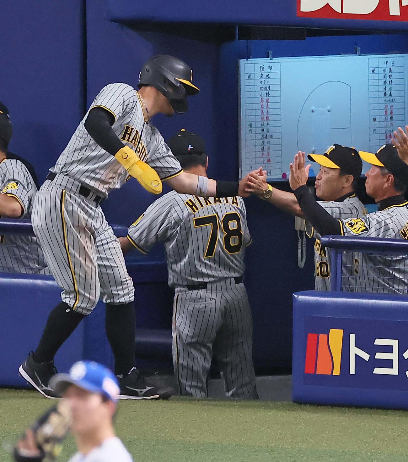 中日対阪神　5回表阪神無死一、三塁、梅野の適時打で生還した佐藤輝（左）は岡田監督（右から2人目）の出迎えを受ける（撮影・上田博志）