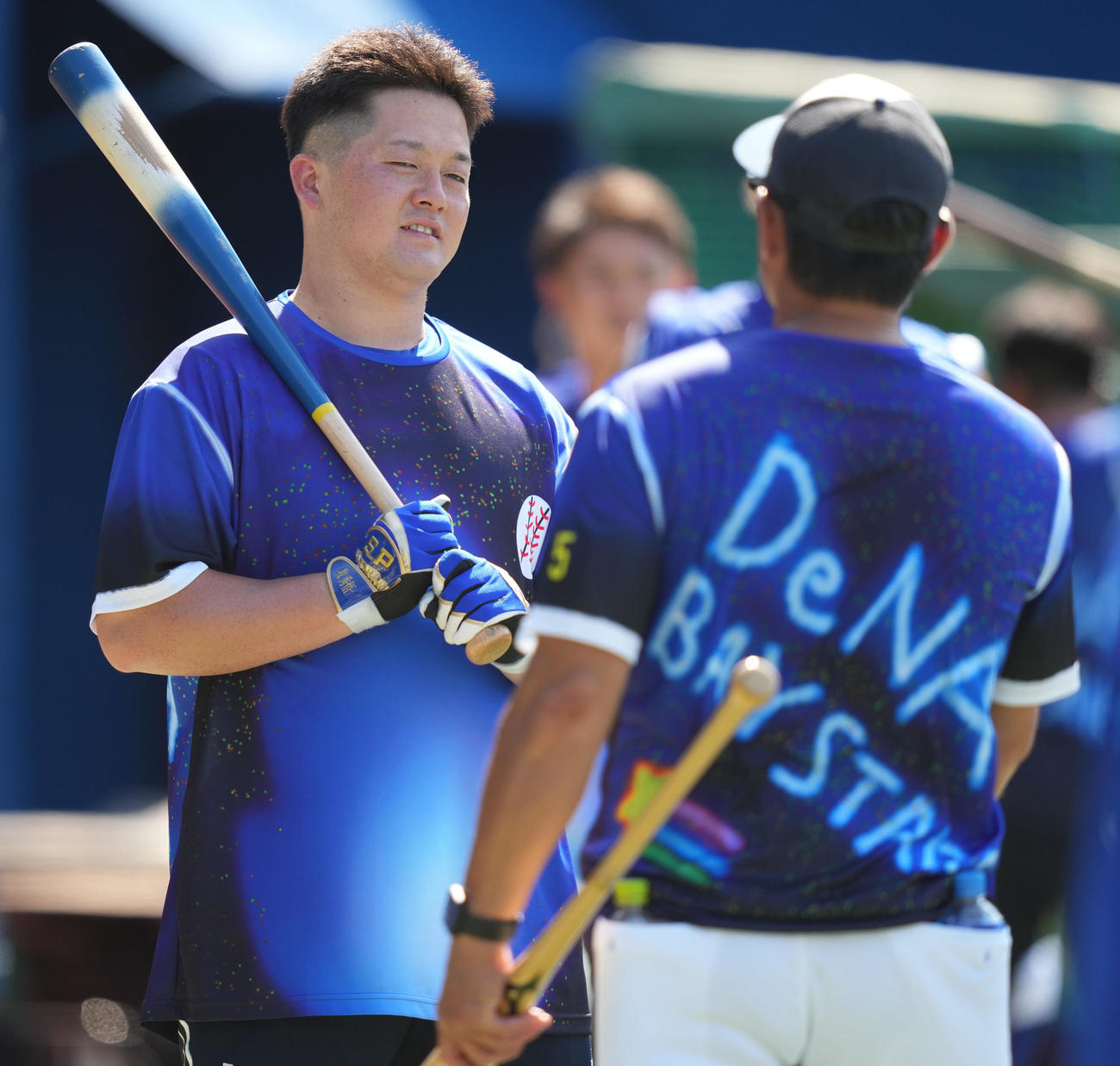 DeNA対阪神　試合前、ファンの子どもがデザインした練習着で石井コーチ（手前）と談笑する牧（撮影・狩俣裕三）