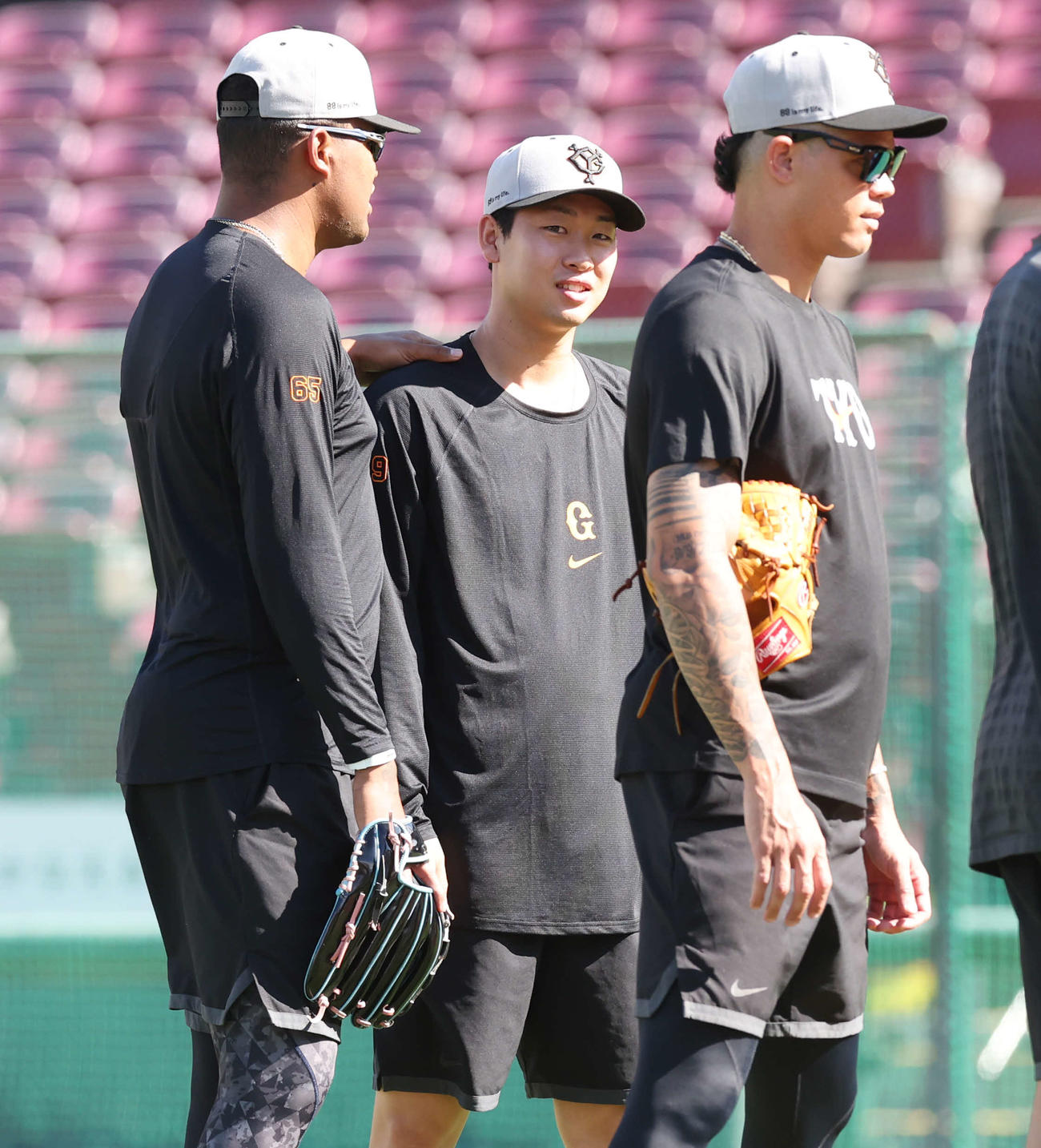 広島対巨人　試合前、巨人メンデス（左）に肩をたたかれる山崎伊（中央）。右はロペス（撮影・宮地輝）