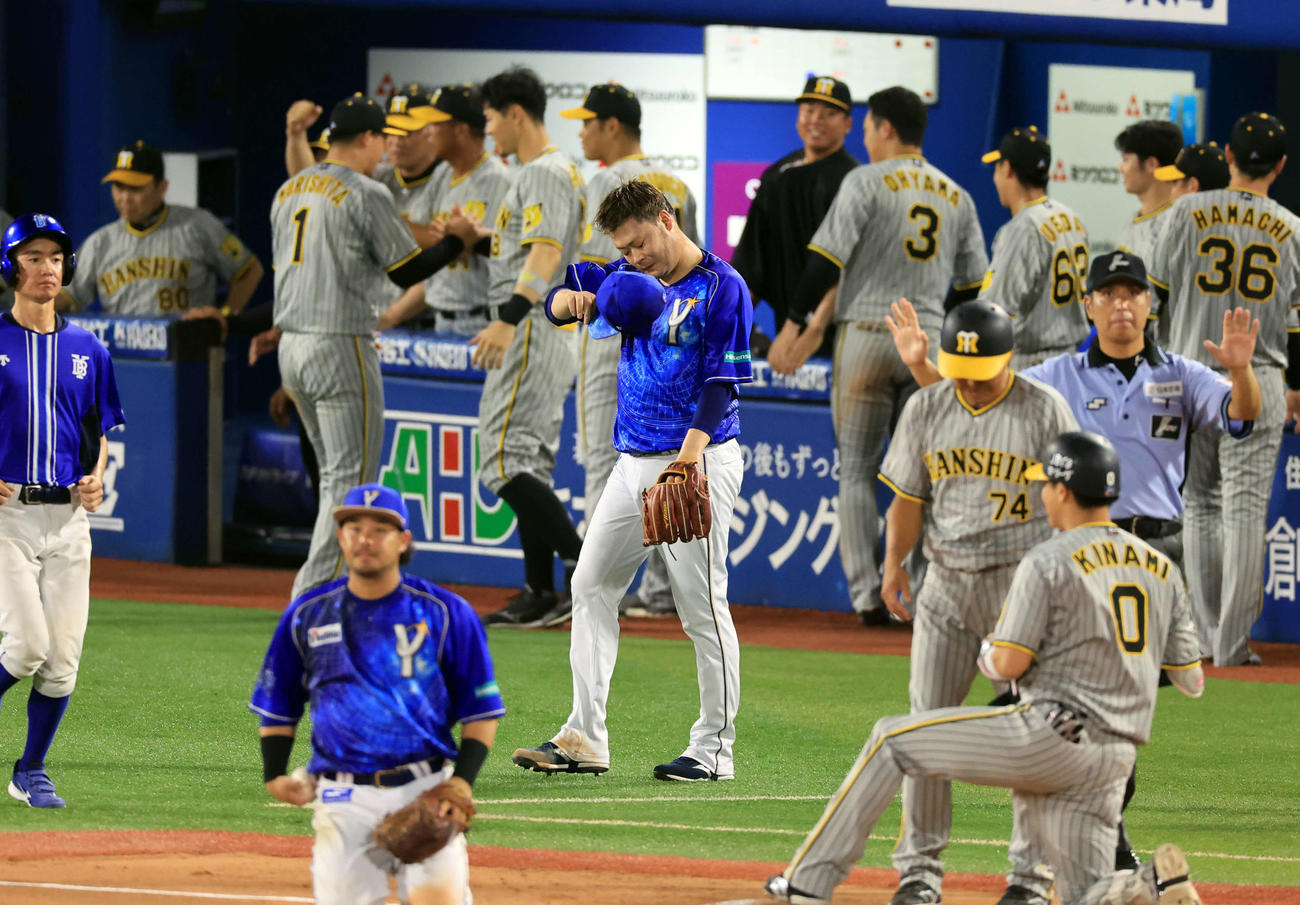 DeNA対阪神　8回表阪神2死一、二塁、木浪（手前右）に勝ち越し2点適時二塁打を許した伊勢（中央）は、喜ぶ阪神ベンチを背に悔しそうに汗をぬぐう（撮影・浅見桂子）