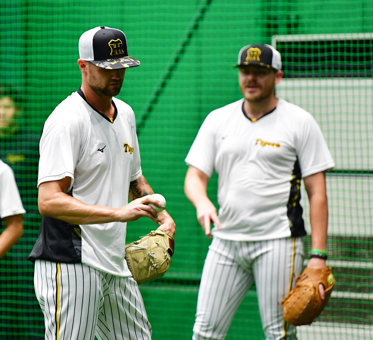 ビーズリー（右）から変化球を教わる阪神の新外国人ブルワー（撮影・清水貴仁）