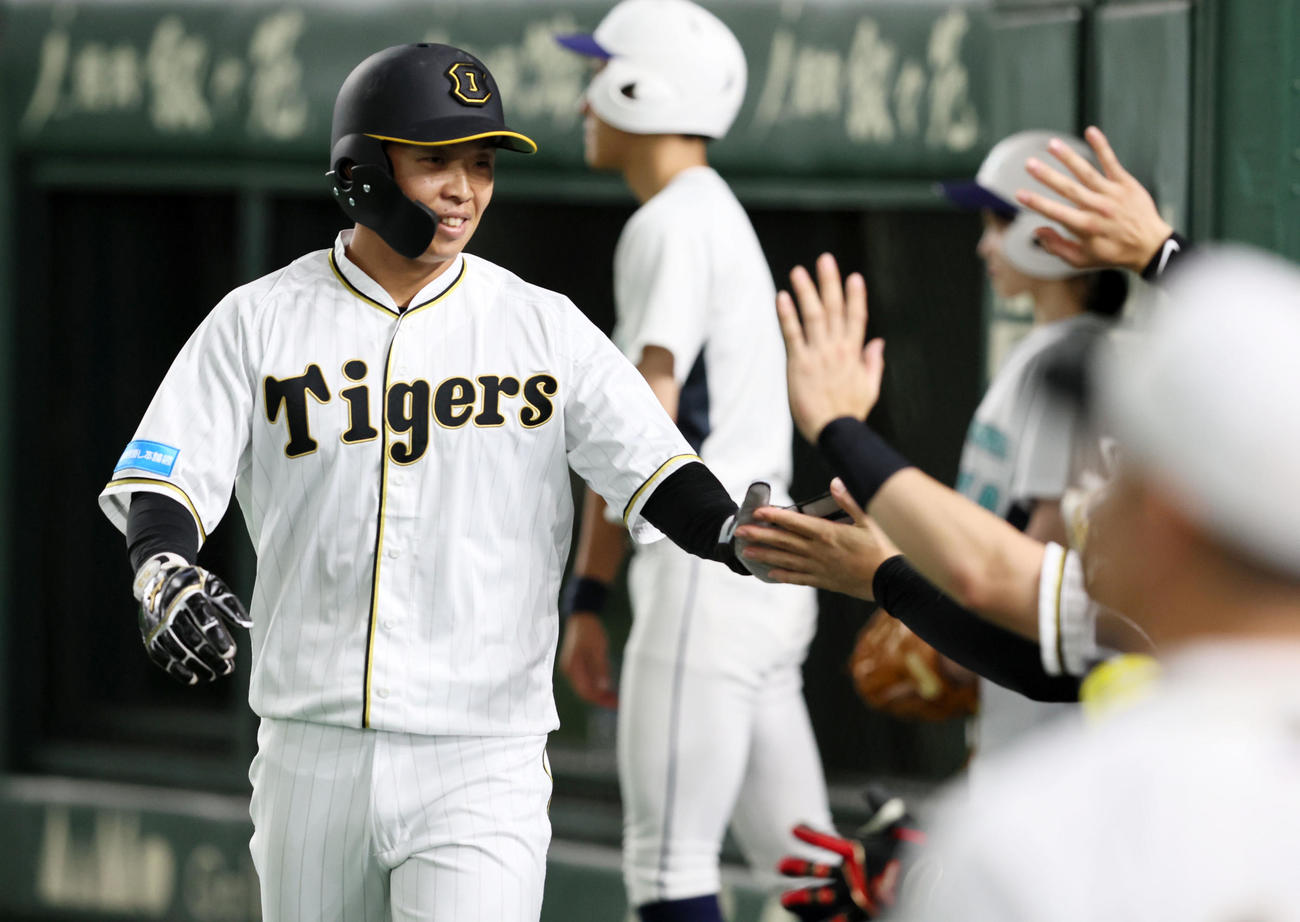 巨人対阪神　7回表阪神無死一、三塁、三塁走者代走島田は相手のけん制球エラーの間に生還しベンチのナインと笑顔でタッチ（撮影・加藤哉）