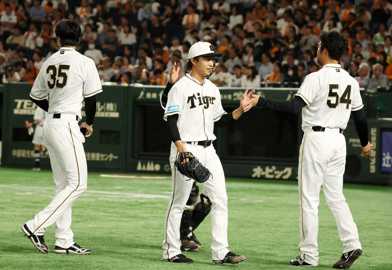 巨人対阪神　8回裏巨人2死一、三塁、阪神3番手で登板の島本が代打岸田を三ゴロに仕留め加治屋（右）の出迎えを受ける。左は先発才木（撮影・加藤哉）
