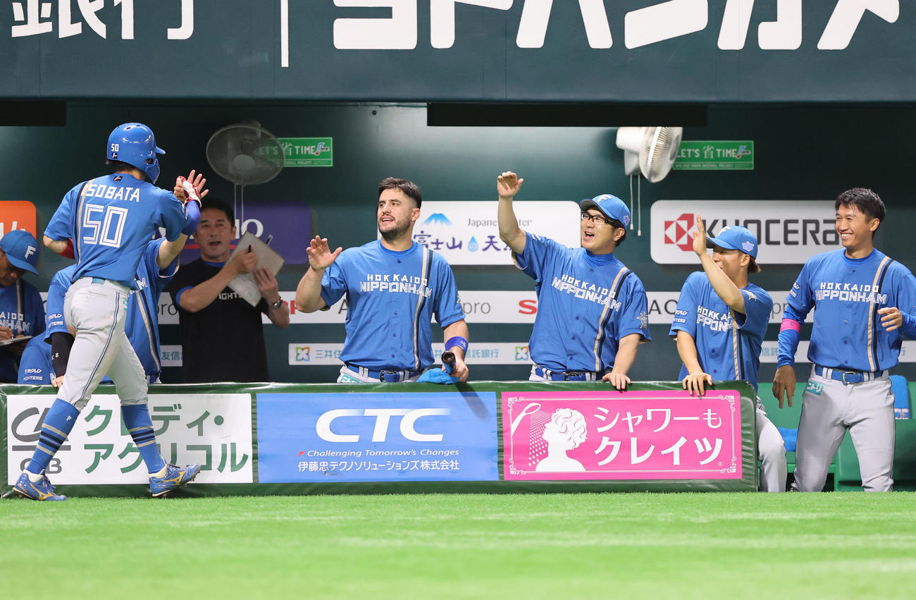 ソフトバンク対日本ハム　1回表日本ハム2死一、二塁、五十幡（左）は万波の先制左前適時打により生還しベンチのナインとタッチを交わす（撮影・冨田成美）