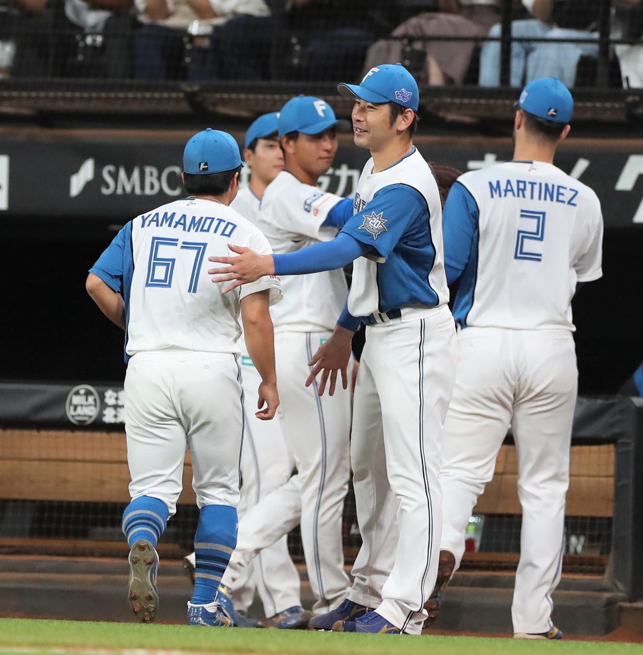 日本ハム対ロッテ　6回表、途中登板の山本拓を出迎える加藤貴（撮影・黒川智章）