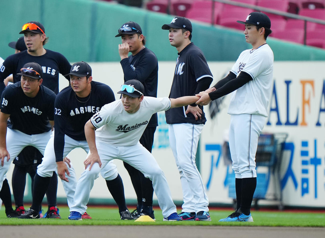 楽天対ロッテ　試合前練習でのウオーミングアップで、ロッテ友杉（手前左）の手をひっぱる小島（撮影・江口和貴）