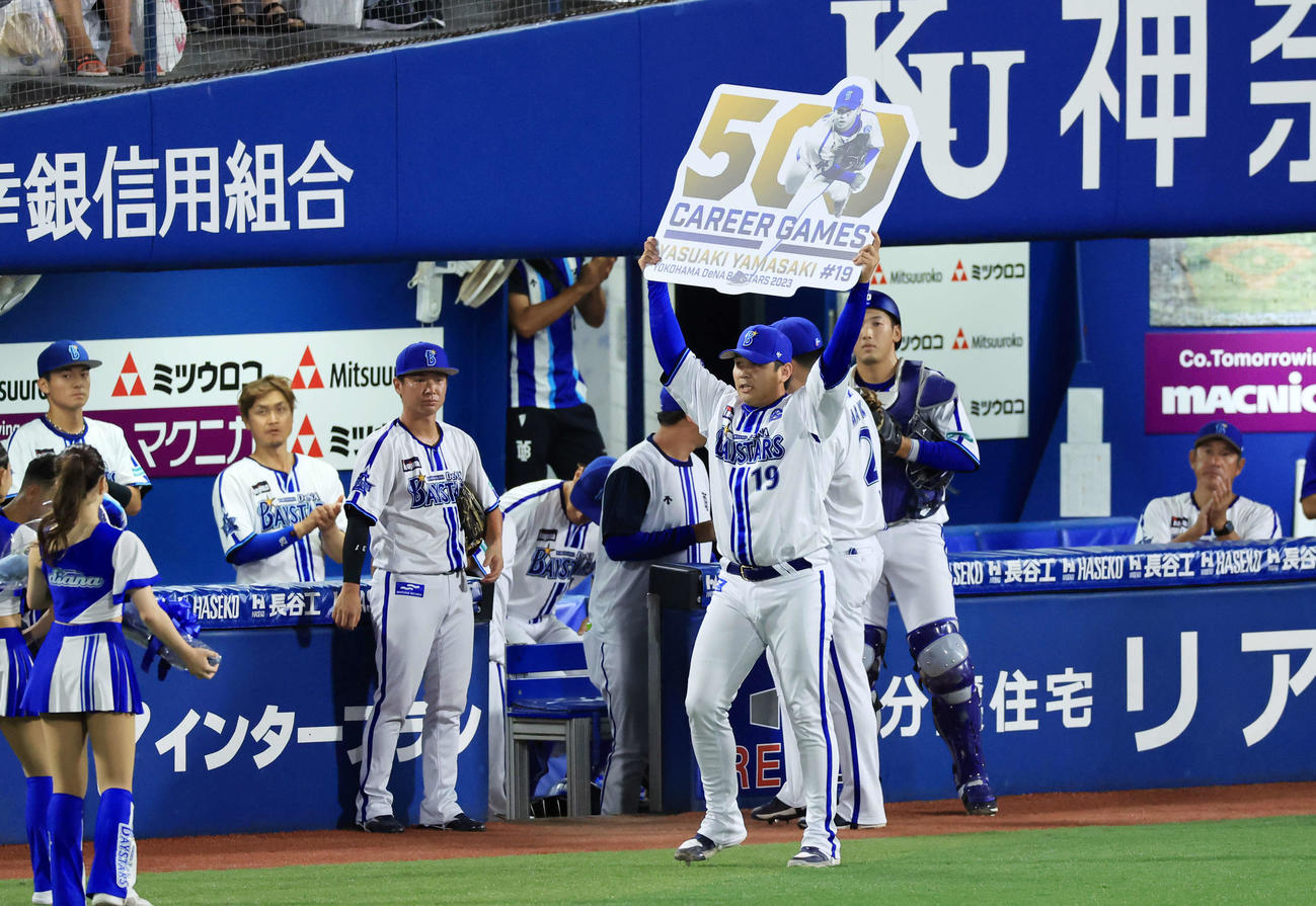DeNA対阪神　9回表阪神の攻撃を抑えた山崎は500試合出場達成のボードを掲げる（撮影・浅見桂子）