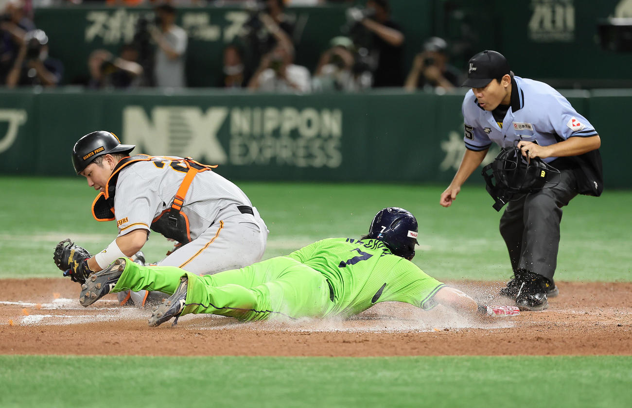 巨人対ヤクルト　6回表ヤクルト1死一、三塁、中村のスクイズで生還した三塁走者長岡（右）。捕手大城卓（撮影・足立雅史）