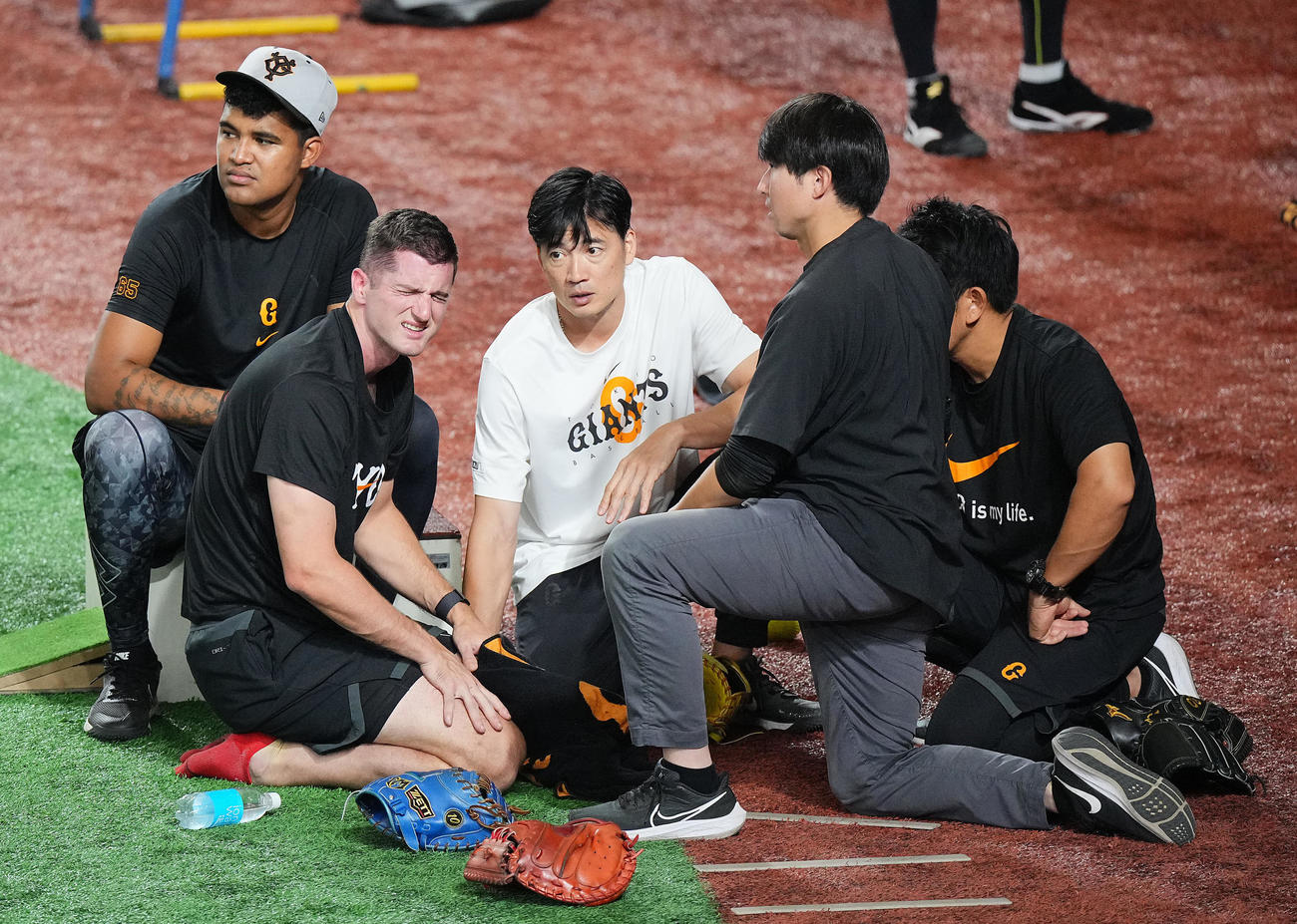 巨人対ヤクルト　試合前練習中、ボールが頭部に当たりうずくまる巨人グリフィン（左）（撮影・垰建太）