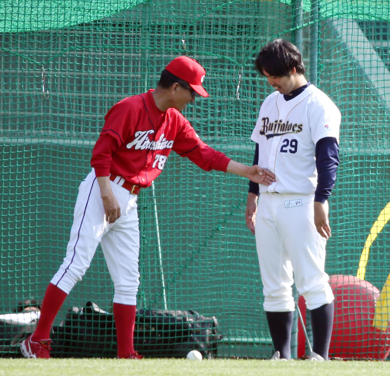 あいさつに来たオリックス井川（右）のおなかを触る広島古沢コーチ