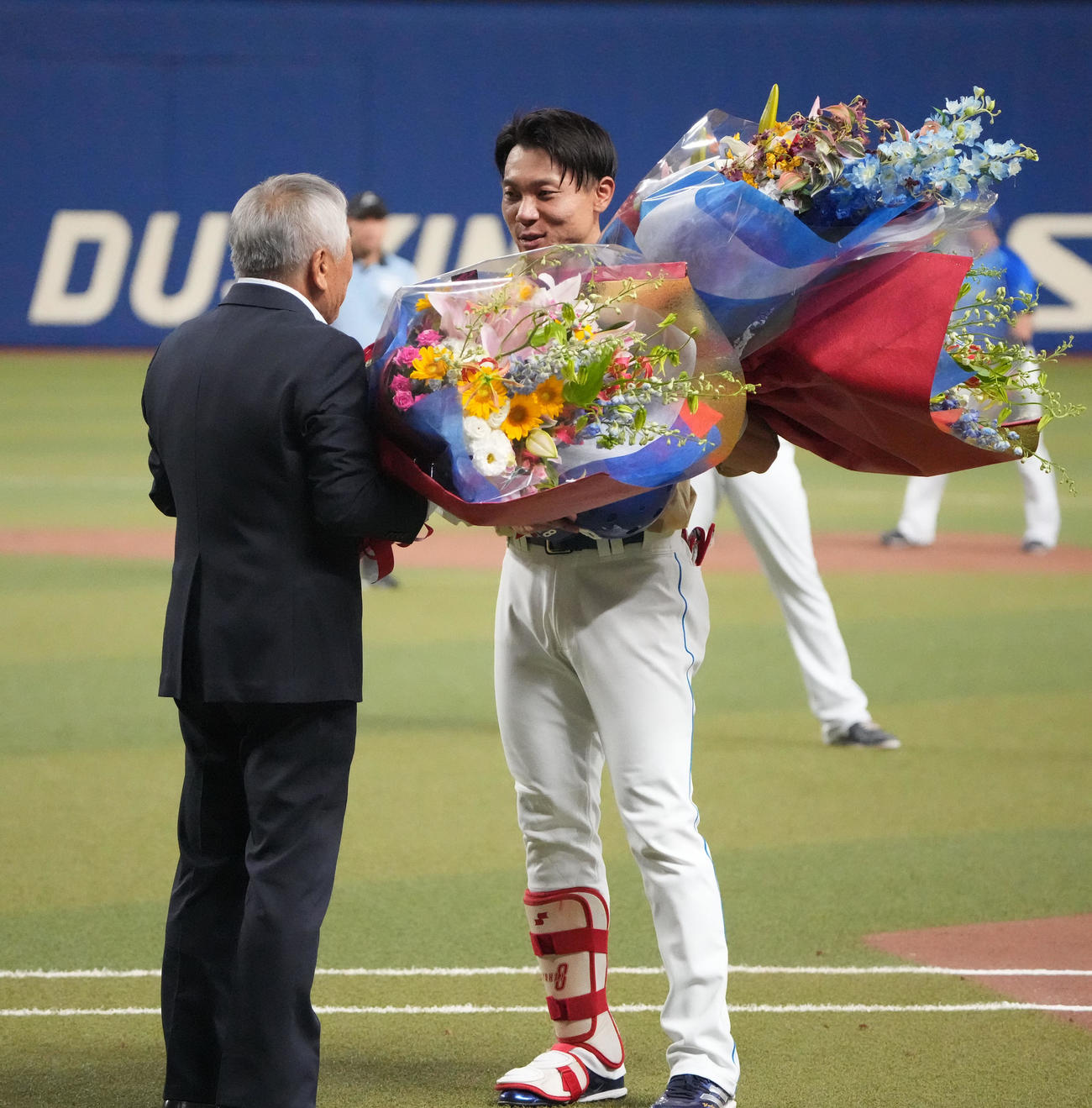 中日対DeNA 3回裏中日1死一塁、中前安打を放ち通算2000本安打を達成し元享栄高校野球部監督の柴垣旭延氏から花束を受け取る大島（右）（撮影・森本幸一）