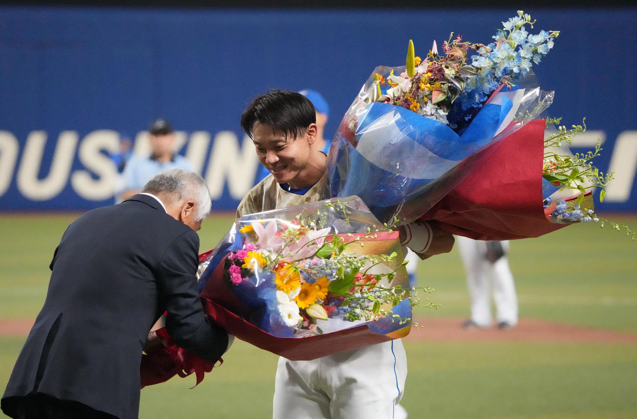 中日対DeNA 3回裏中日1死一塁、中前安打を放ち通算2000本安打を達成し元享栄高校野球部監督の柴垣旭延氏から花束を受け取る大島（右）（撮影・森本幸一）