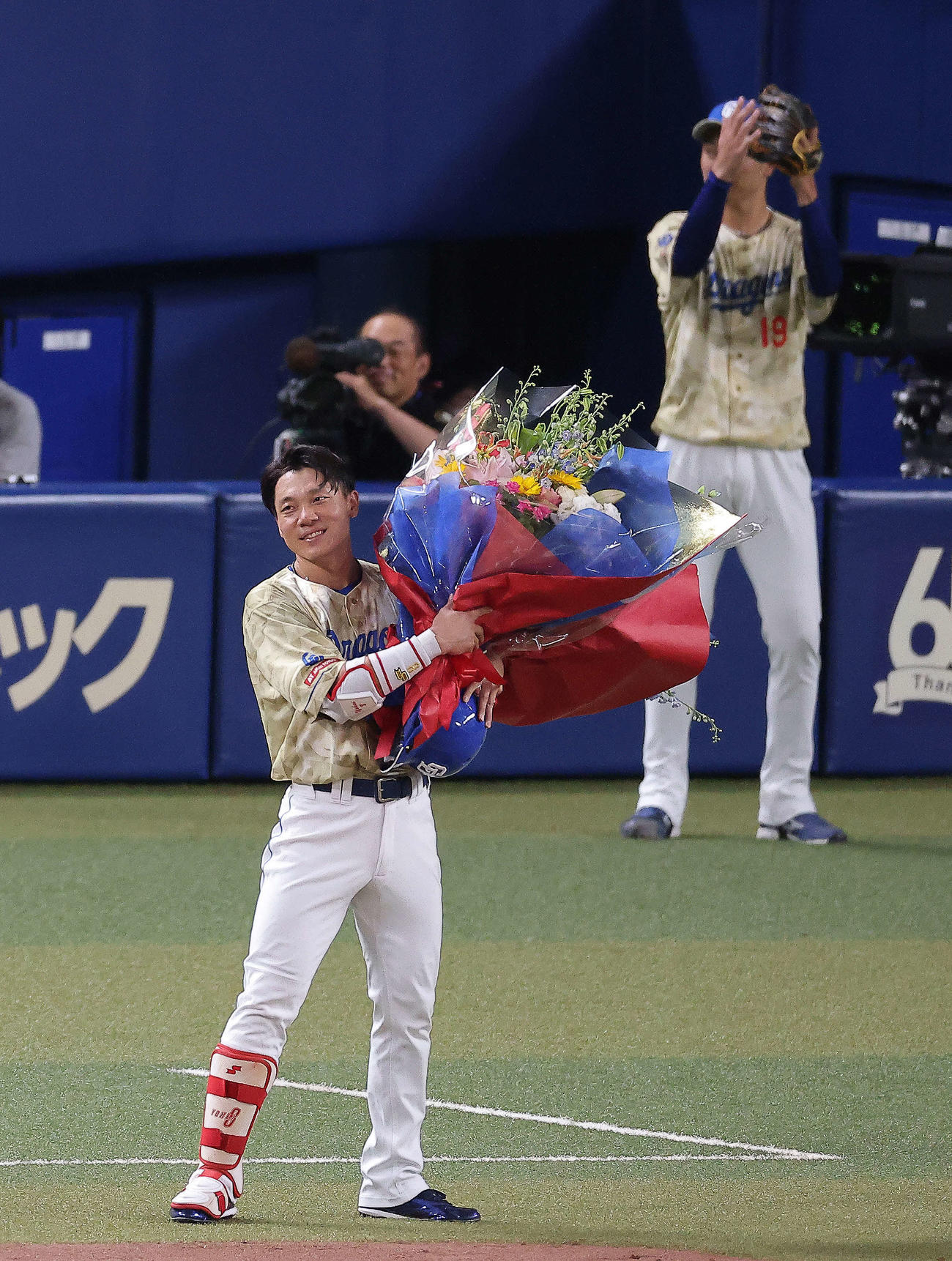 中日対DeNA 3回裏中日1死一塁、通算2000安打となる中前打を放ち、花束を手に笑顔を見せる大島洋平。後方右は高橋宏（撮影・河田真司）