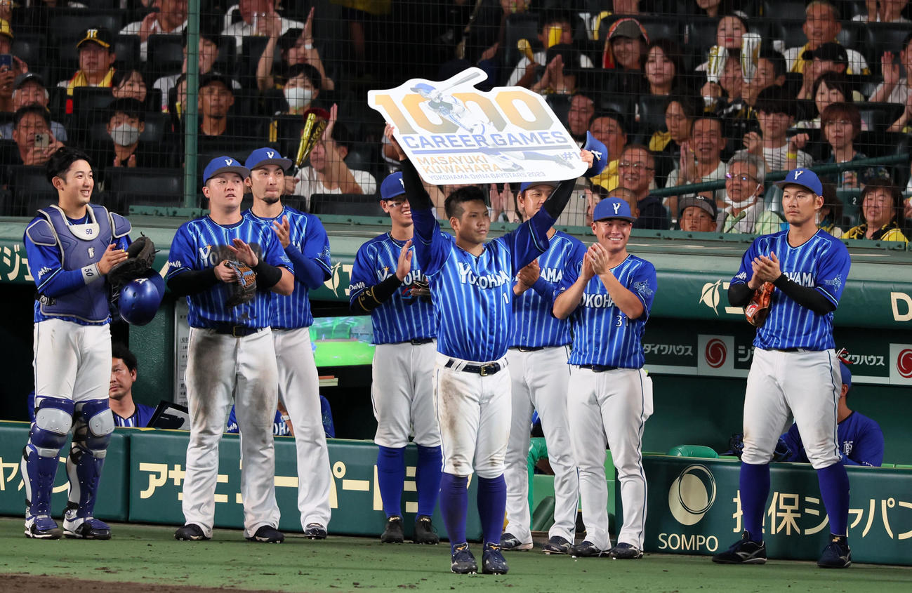 阪神対DeNA 5回裏を終えDeNA桑原は1000試合出場を達成し記念のボードを掲げる（撮影・加藤哉）