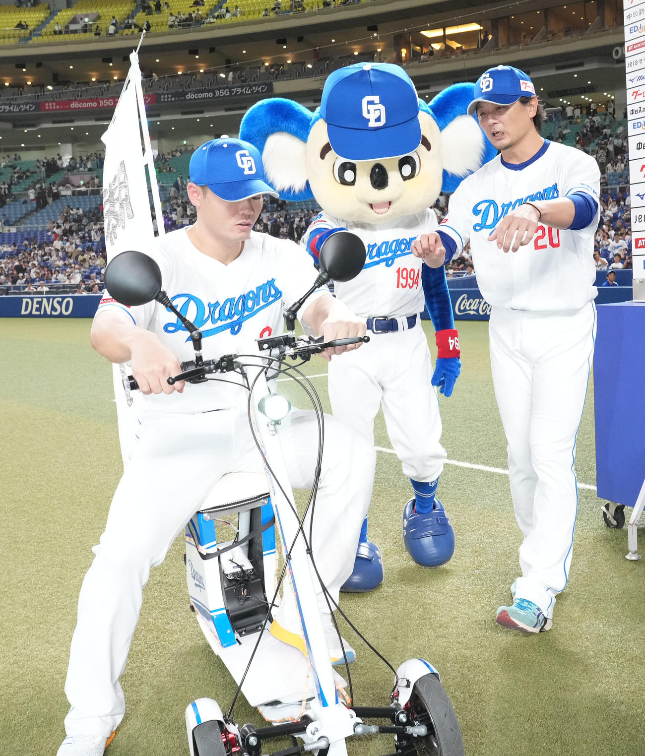 中日対ヤクルト　ビクトリーショーでドアラが使用するバイクに涌井（右）の指示でまたがる細川（撮影・森本幸一）