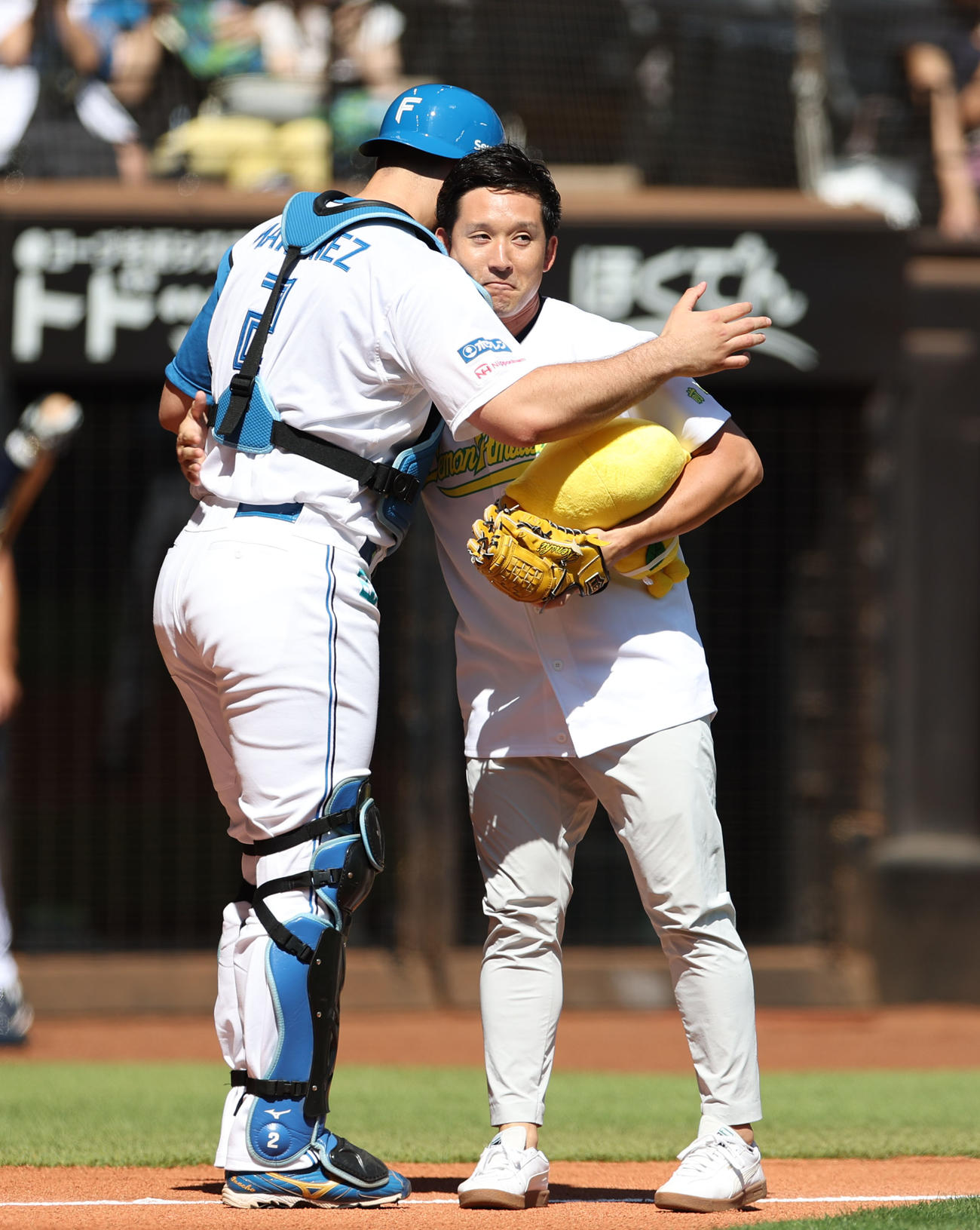 試合前、始球式を務め日本ハム・マルティネス（左）と抱き合う杉谷氏（撮影・佐藤翔太）