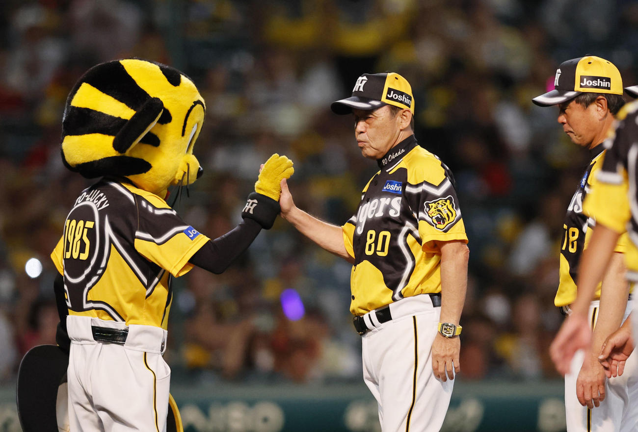トラッキー（左）とタッチを交わす阪神岡田監督（2023年7月30日撮影）