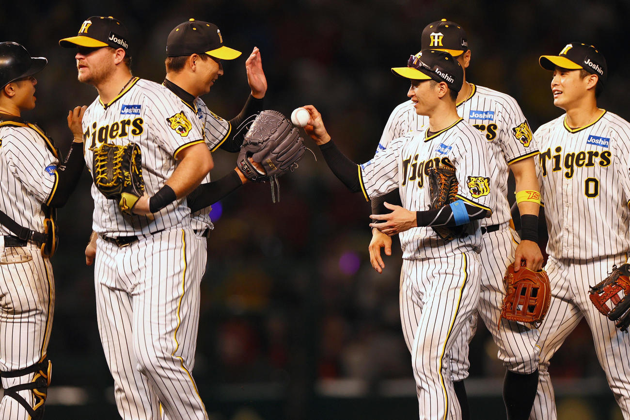 阪神対広島　広島に勝利し、30セーブをマークした阪神岩崎（左から3人目）にウイニングボールを手渡す近本（右から3人目）（撮影・上山淳一）