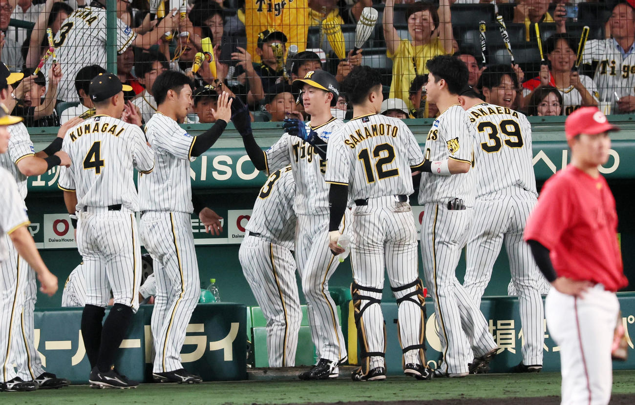 阪神対広島　8回裏阪神2死一塁、大山の左適時二塁打で生還した一塁走者近本はベンチ前でナインとタッチする（撮影・加藤哉）