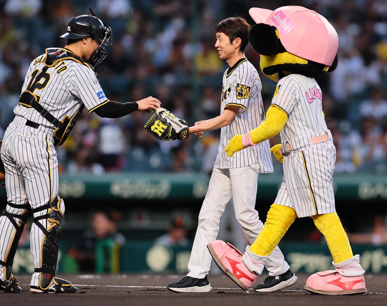 阪神対巨人　始球式を務めた騎手の武豊氏（中央）は坂本誠志郎からボールを受け取る（撮影・上田博志）