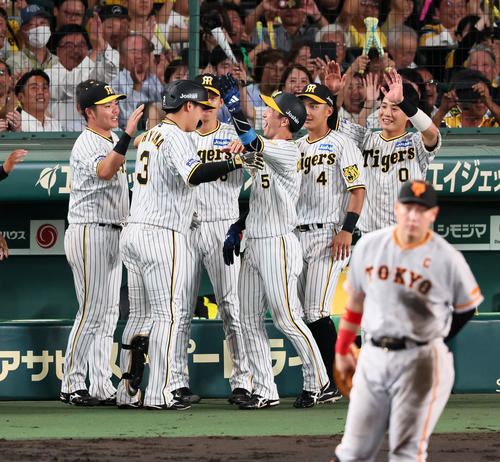 阪神対巨人 6回裏阪神1死一、三塁、大山は中犠飛を打ち上げ生還した三塁走者近本(右)から笑顔でヘルメットを叩かれる(撮影・加藤哉)