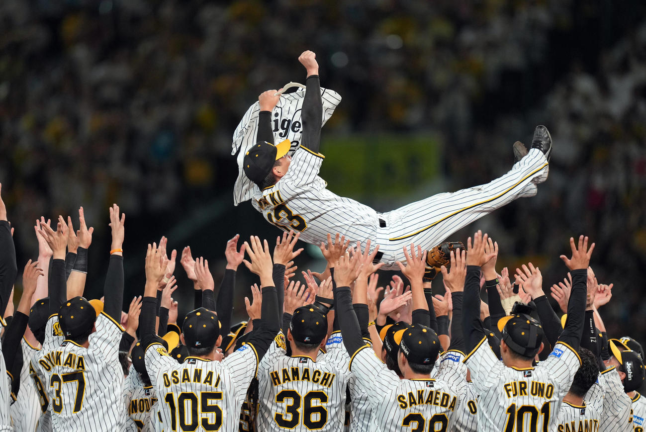 阪神対巨人　故横田慎太郎さんのユニホームを持ちながら、胴上げされる岩崎（撮影・狩俣裕三）