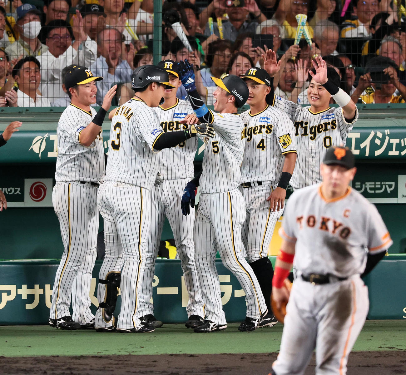 阪神対巨人　6回裏阪神1死一、三塁、大山は中犠飛を打ち上げ生還した三塁走者近本（右）から笑顔でヘルメットを叩かれる（撮影・加藤哉）