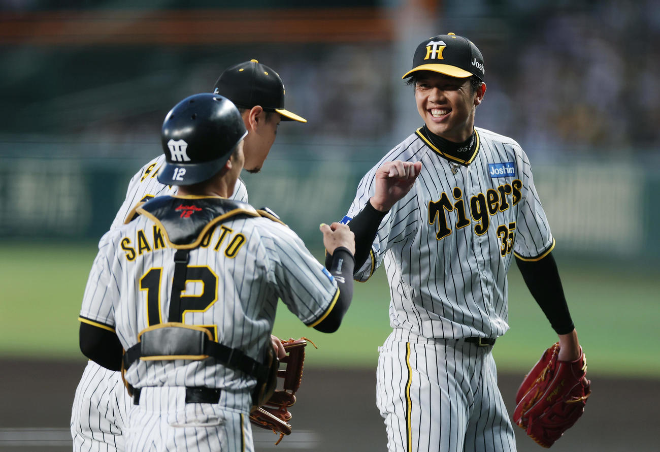 阪神対巨人　1回表の巨人打線を3者凡退に抑え、笑顔で阪神坂本（左）とタッチを交わす才木（撮影・前田充）