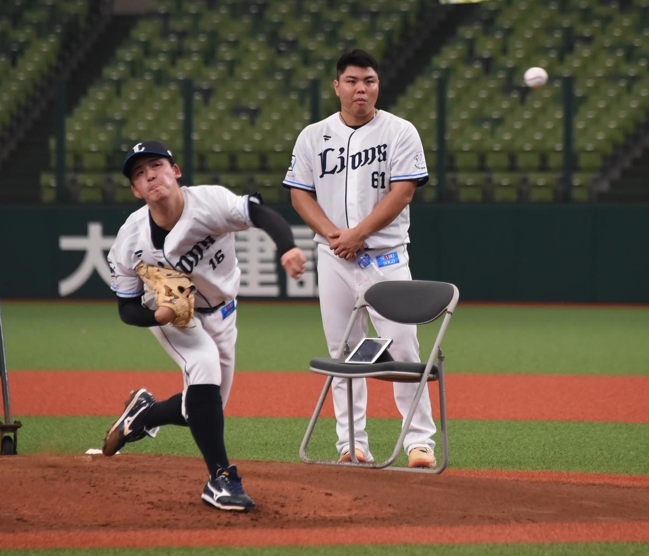 隅田（左）の投球練習を見つめる西武平良（撮影・鈴木正章）