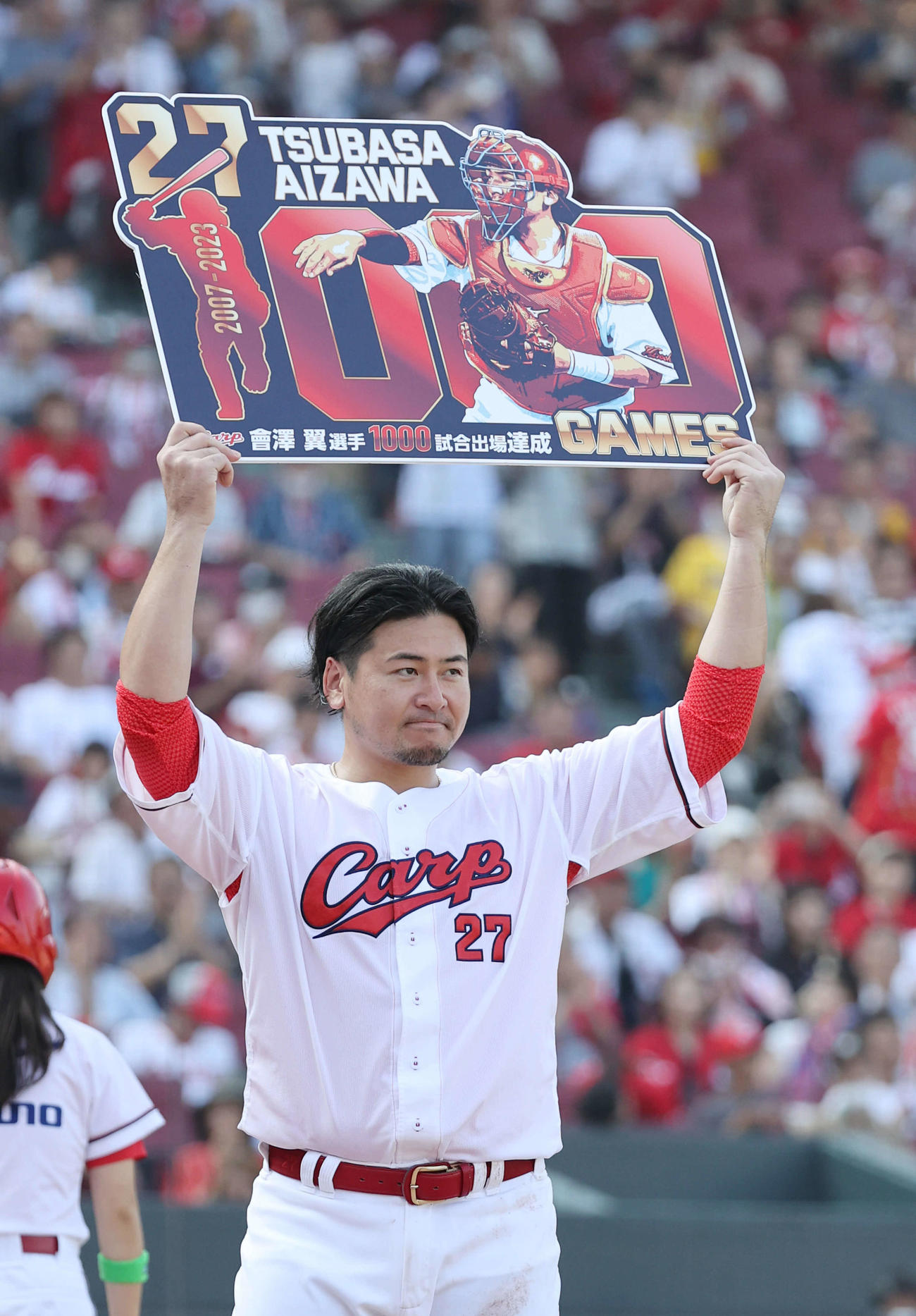 広島対阪神　5回裏終了時、1000試合出場を達成し、記念のボードを掲げる会沢（撮影・加藤孝規）