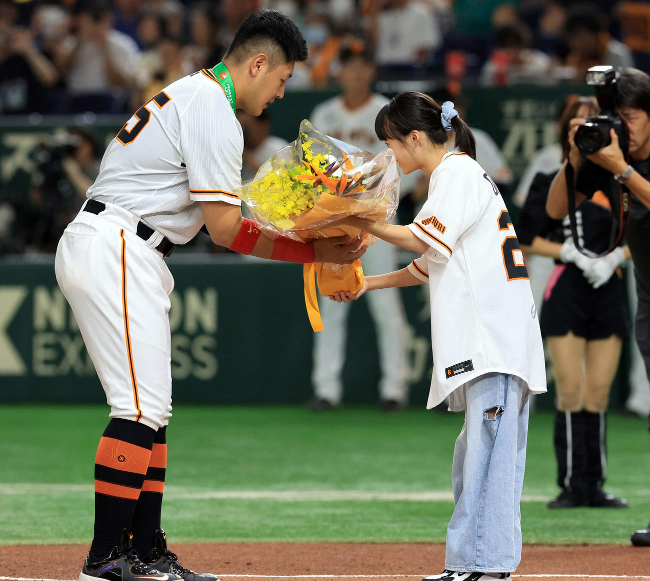 巨人対ヤクルト　通算200本塁打達成の表彰で、ファンの女の子から花束を受け取る巨人岡本和（撮影・浅見桂子）