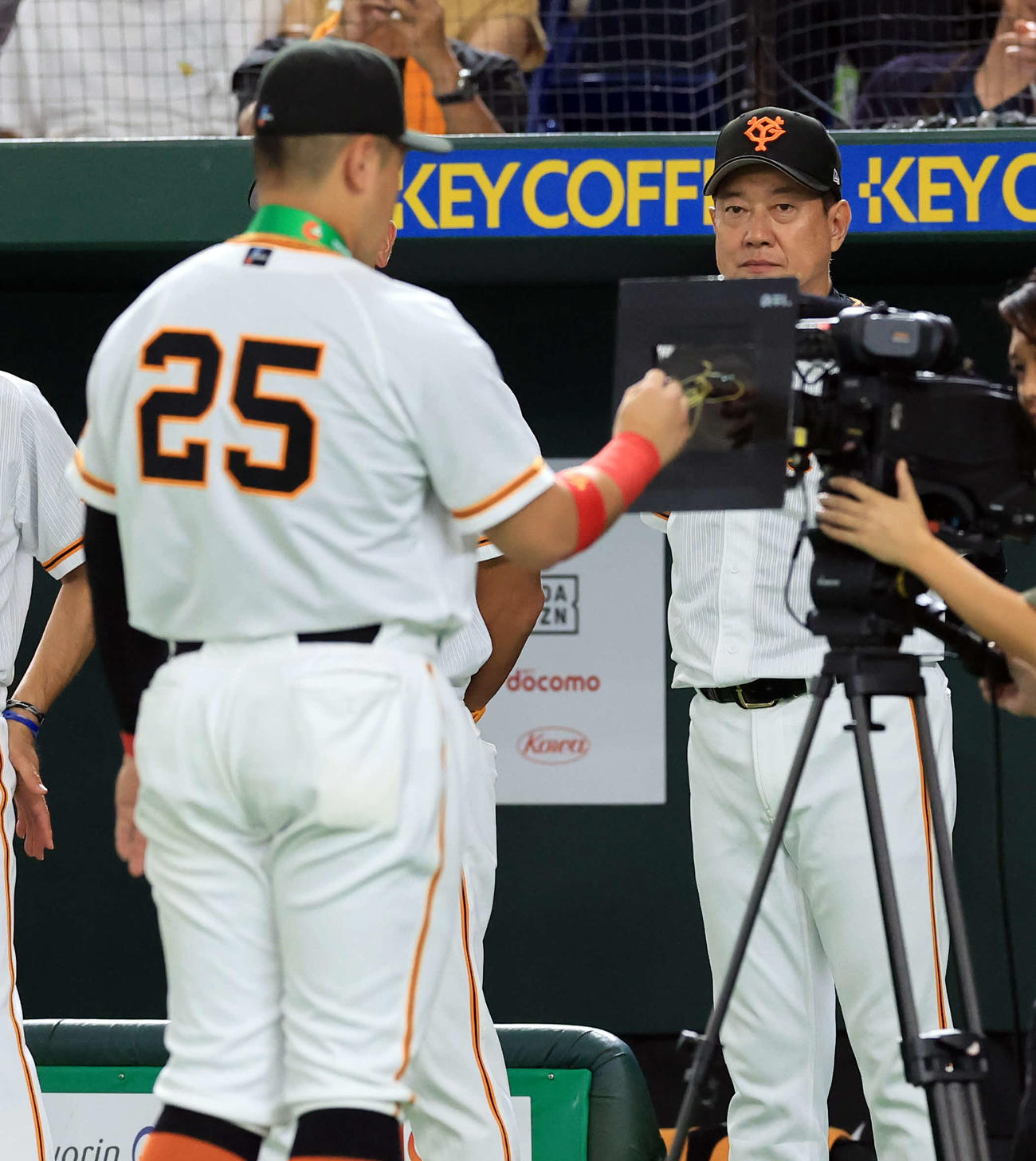巨人対ヤクルト　通算200本塁打達成の表彰で、カメラにサインする巨人岡本和（手前）を見つめる原監督（撮影・浅見桂子）