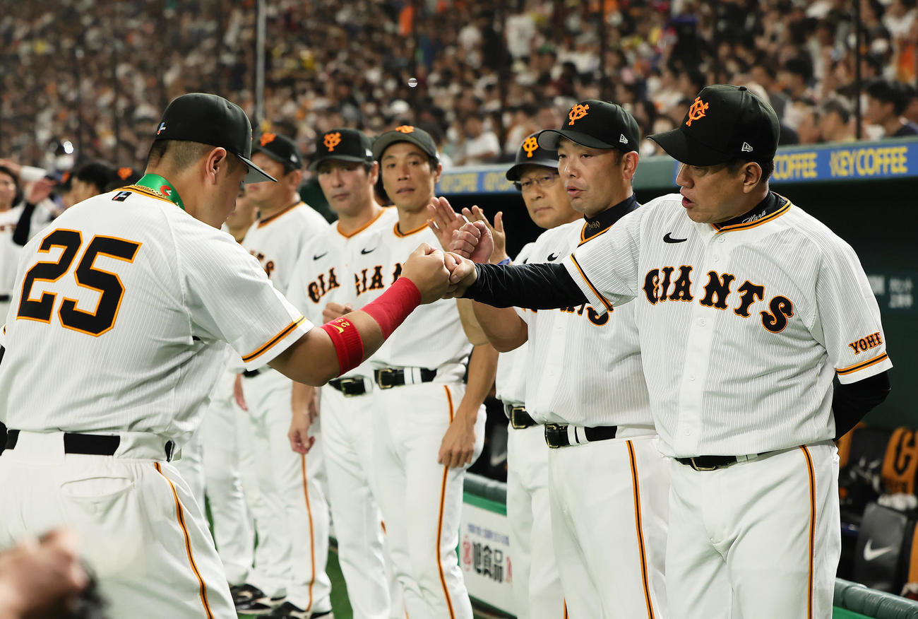 試合前、通算200本塁打の連盟表彰を受けた巨人岡本和（左）は原監督にグータッチで迎えられる（撮影・足立雅史）