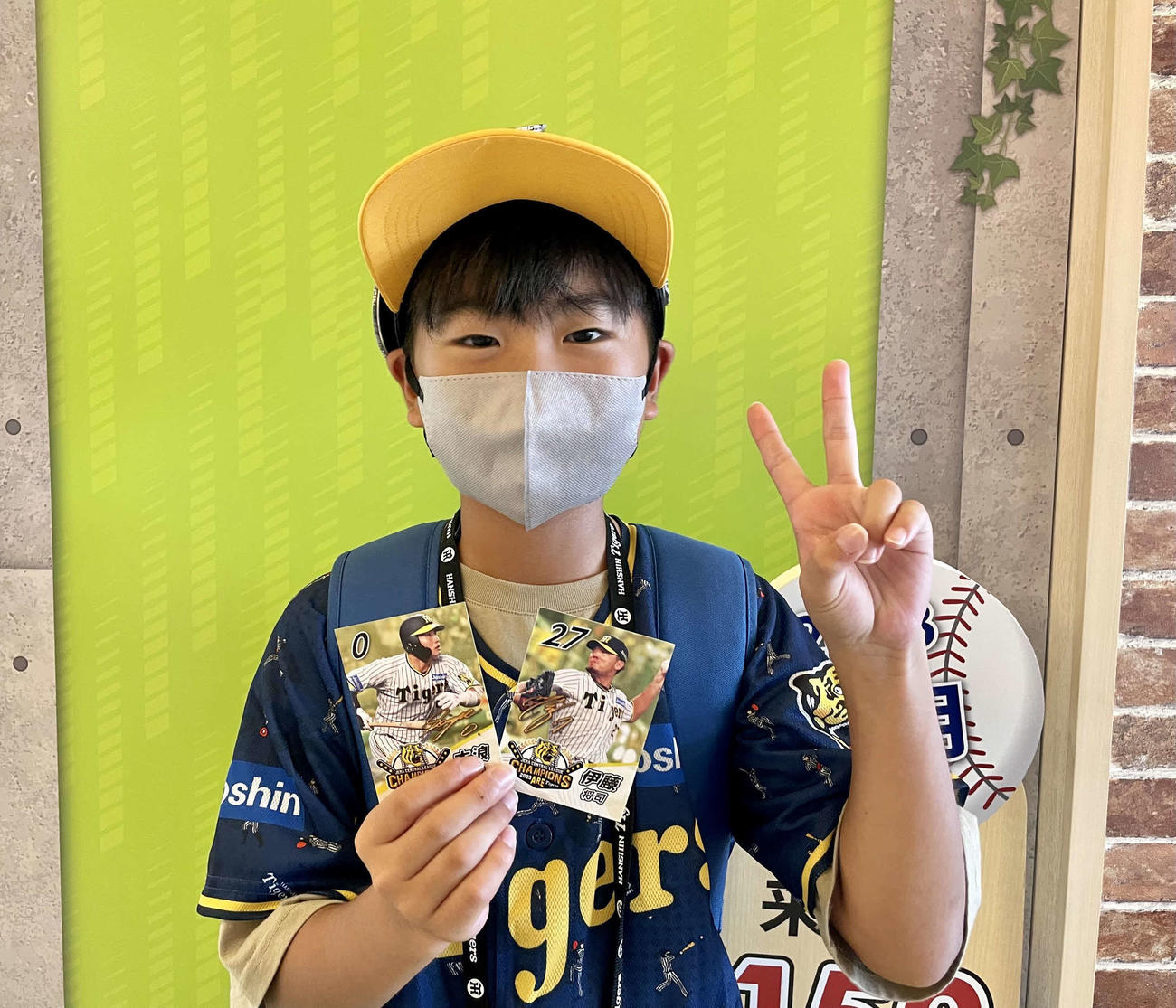 試合観戦前、優勝ペナントが展示中の甲子園歴史館に父岡田彰久さん（51）と訪れた悠聖くん（11）。歴史館で入場者先着4万人に配布される優勝記念カードを無事ゲットしてピースサイン（撮影・中島麗）