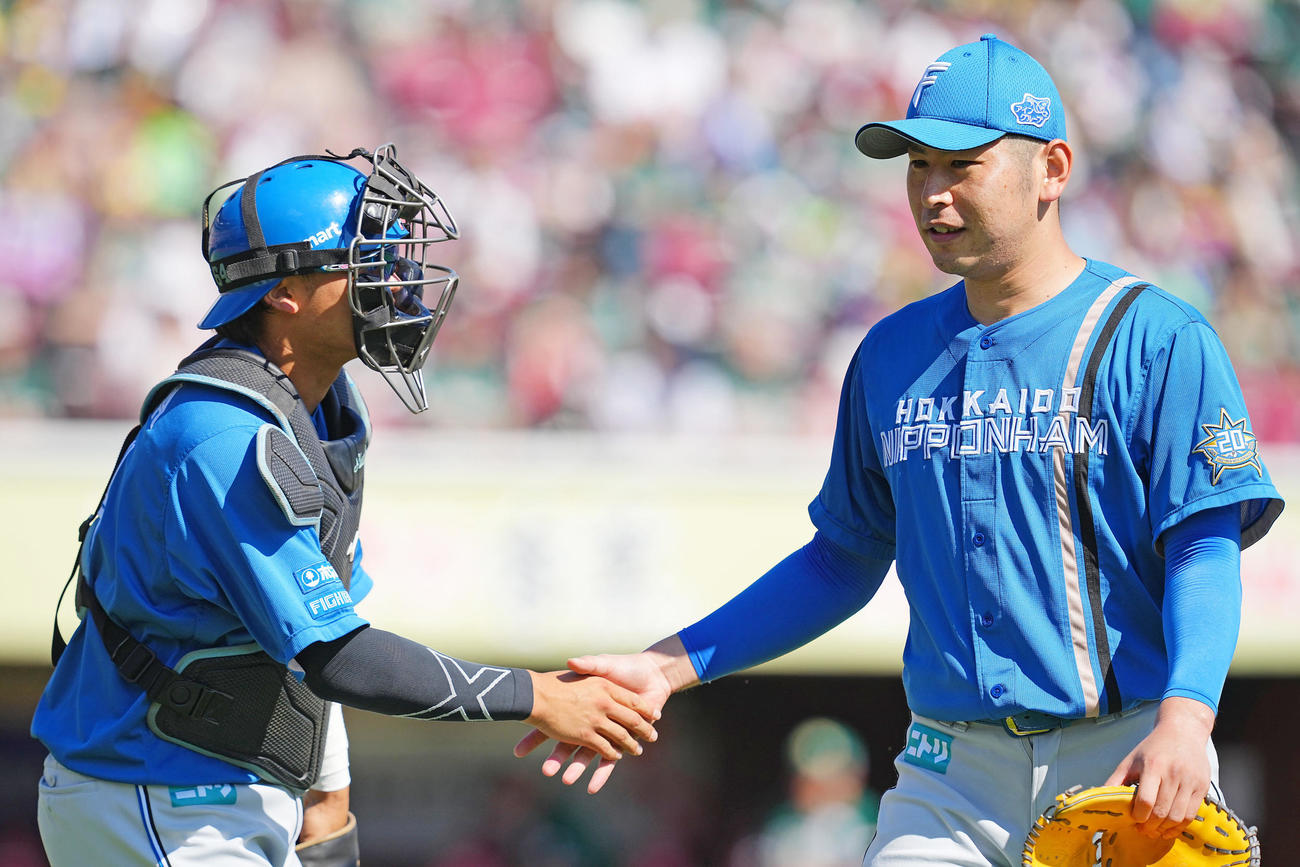 楽天対日本ハム　1回裏楽天の攻撃を無失点に抑えた日本ハム先発の加藤貴（右）は田宮と笑顔でタッチを交わす（撮影・垰建太）