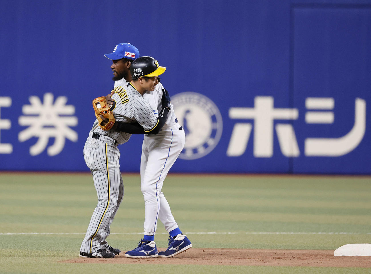 中日対阪神　2回表阪神1死一塁、木浪の一ゴロ併殺でぶつかりそうになり一走坂本（左）を抱きしめる遊撃手カリステ（撮影・藤尾明華）