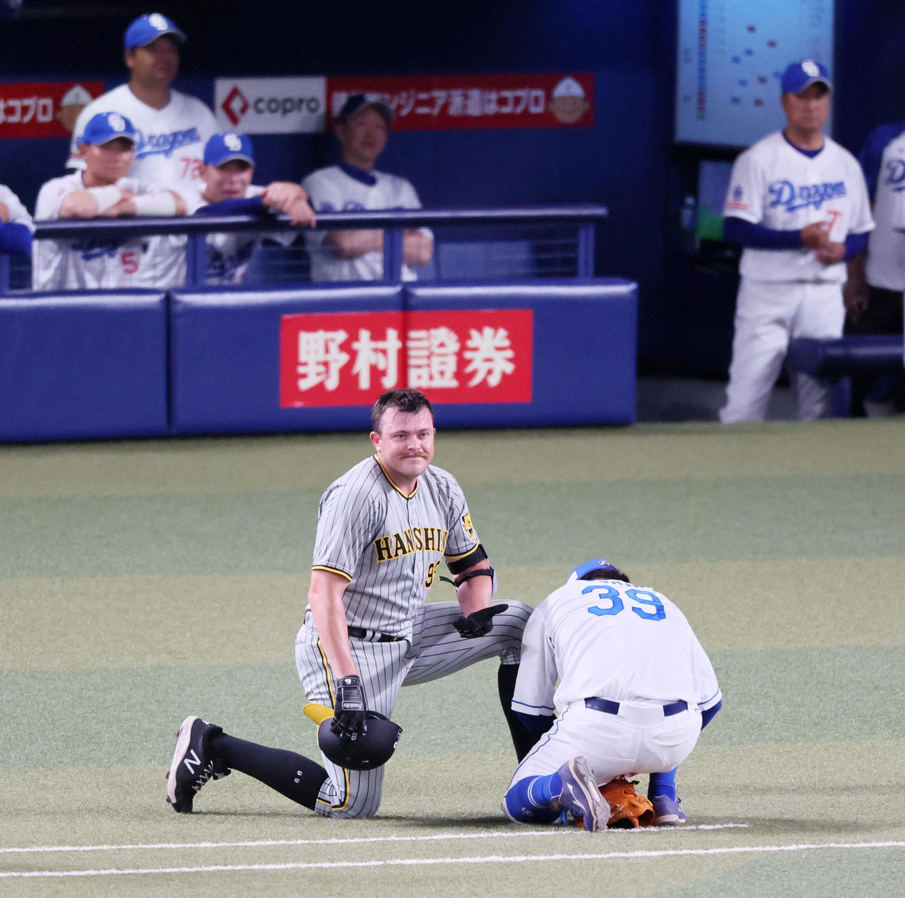 中日対阪神　7回表阪神無死一塁、打者ビーズリー（左）はバントした際に足の防具がはずれ宇佐見が装着の手助けをする（撮影・加藤哉）
