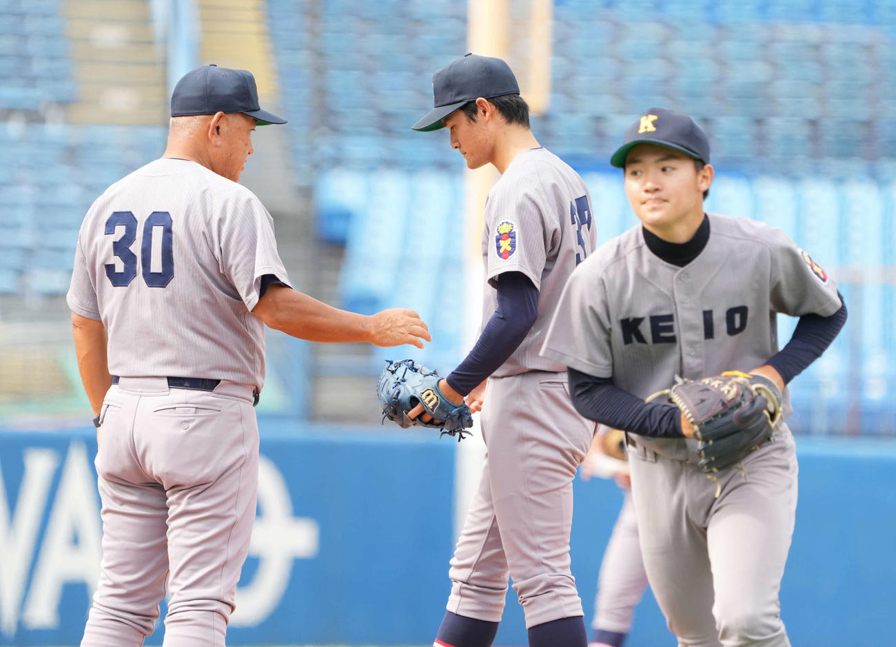法大対慶大　4回表法大2死一塁、慶大・堀井監督（左）は2番手の木暮にボールを手渡す。右は降板する先発の竹内（撮影・小沢裕）