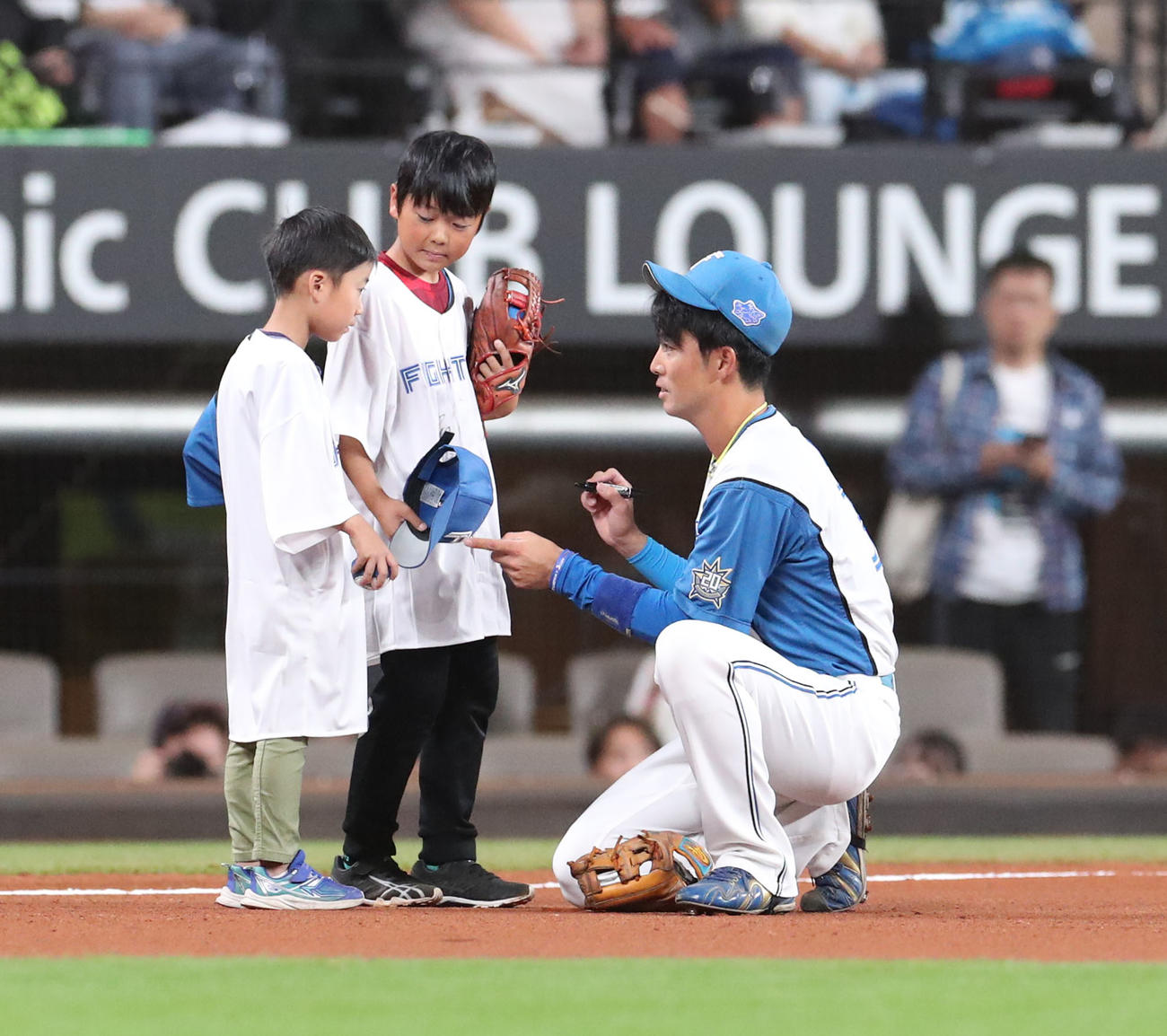 日本ハム対ロッテ　三塁手としてスタメン出場し子どもたちにサインをする日本ハム谷内（撮影・佐藤翔太）