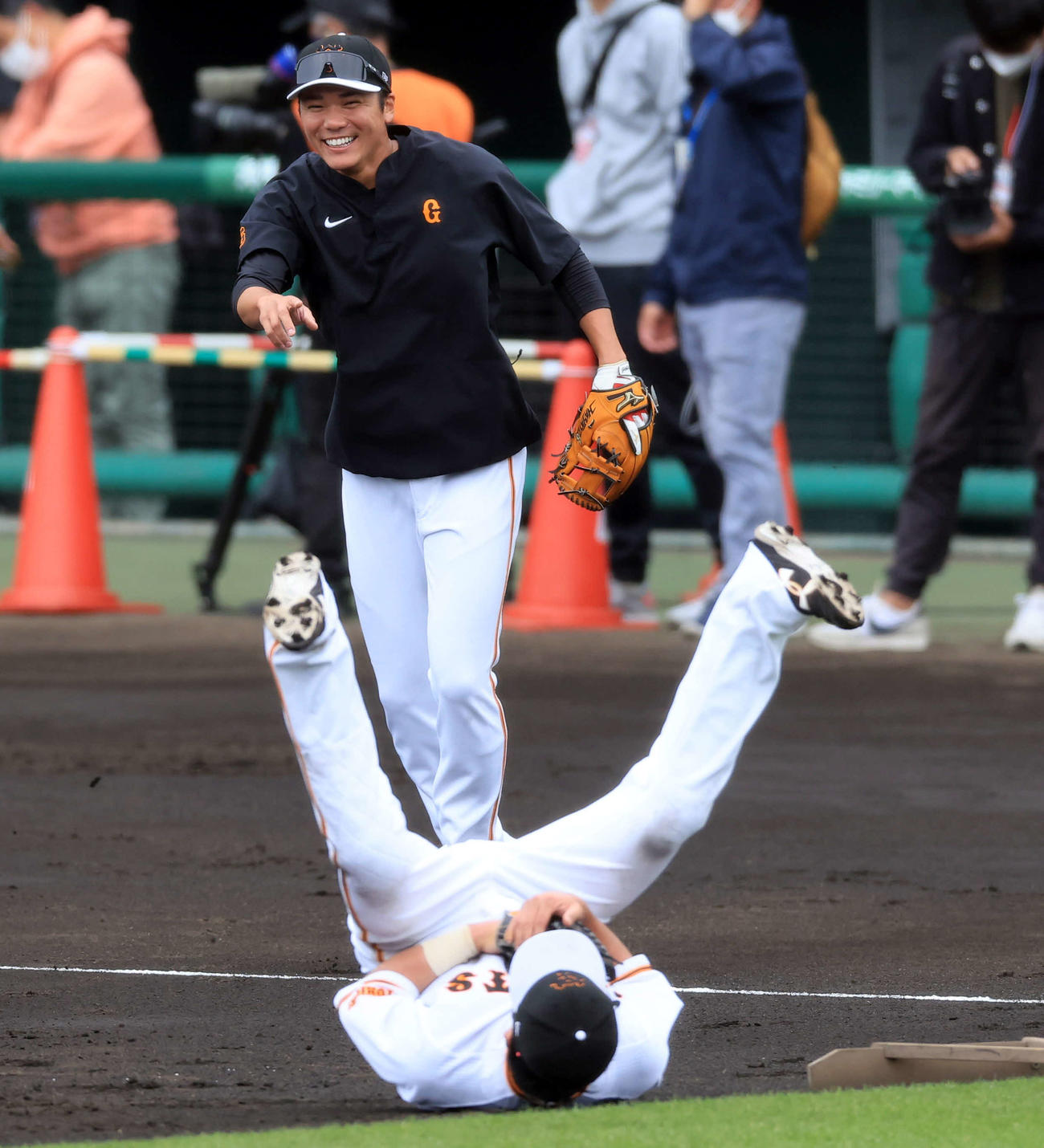 2023年2月、春季キャンプのノック中、捕球してひっくり返った松田（手前）に笑顔を見せる巨人坂本