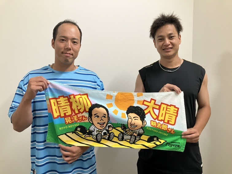 「雨男」の青柳（左）と大竹は「晴れ男」のコラボグッズタオルを掲げて記念撮影（球団提供）