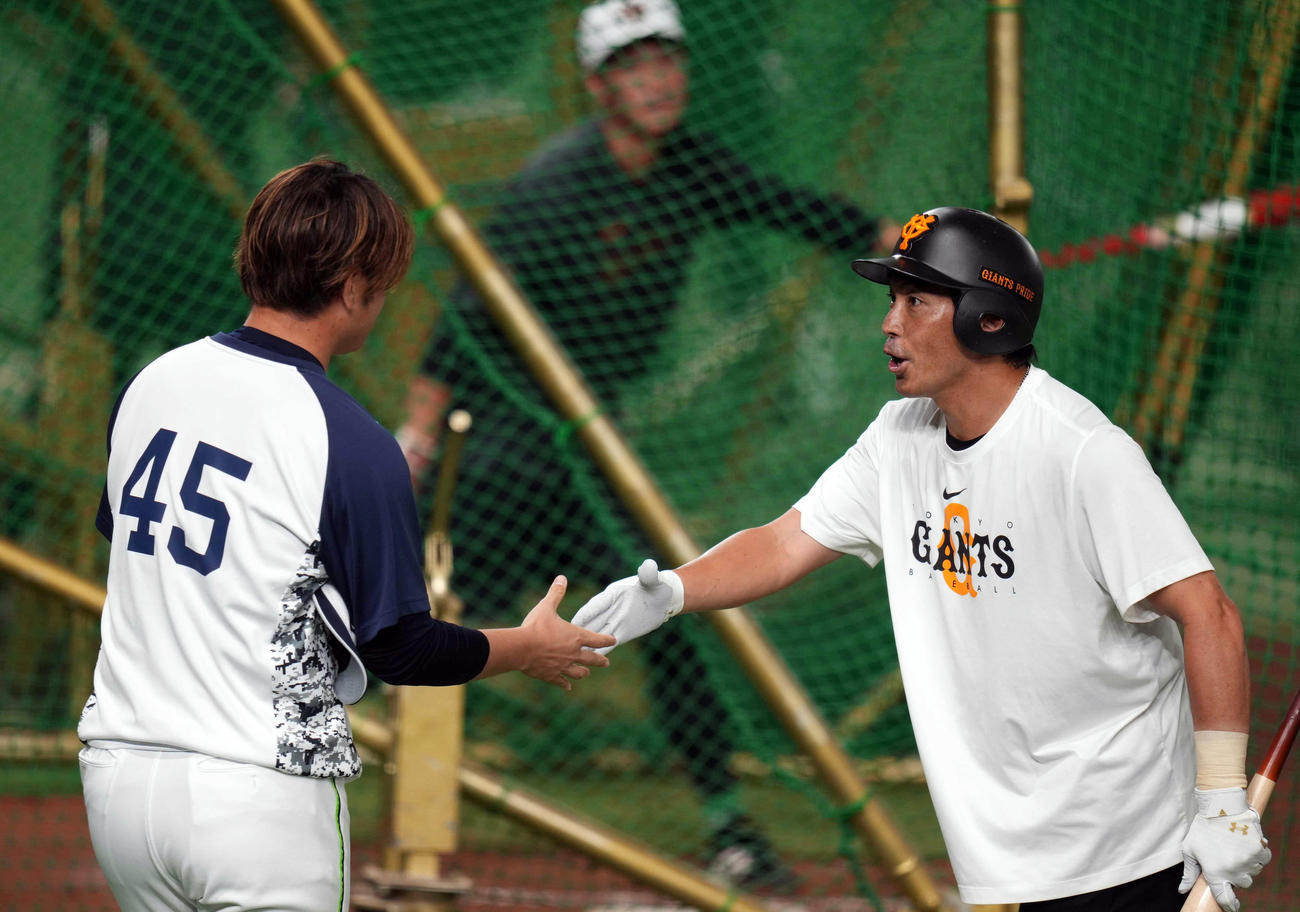 巨人対ヤクルト　試合前、元ソフトバンクの小沢（左）からあいさつされる松田（撮影・狩俣裕三）