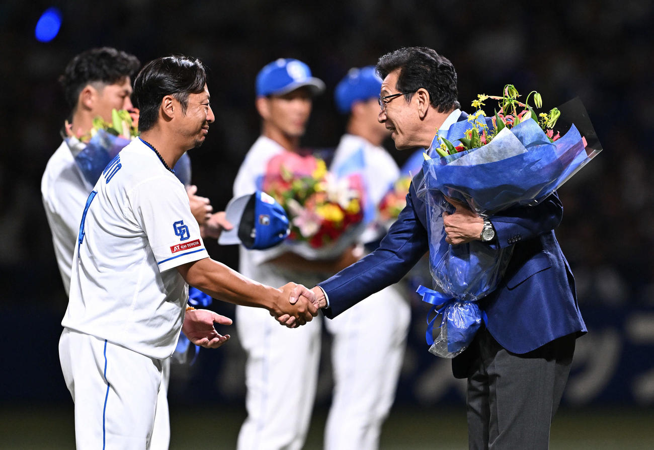 中日対巨人　引退セレモニーで中日谷元（左手前）は花束を贈呈する栗山氏と握手を交わす（撮影・滝沢徹郎）