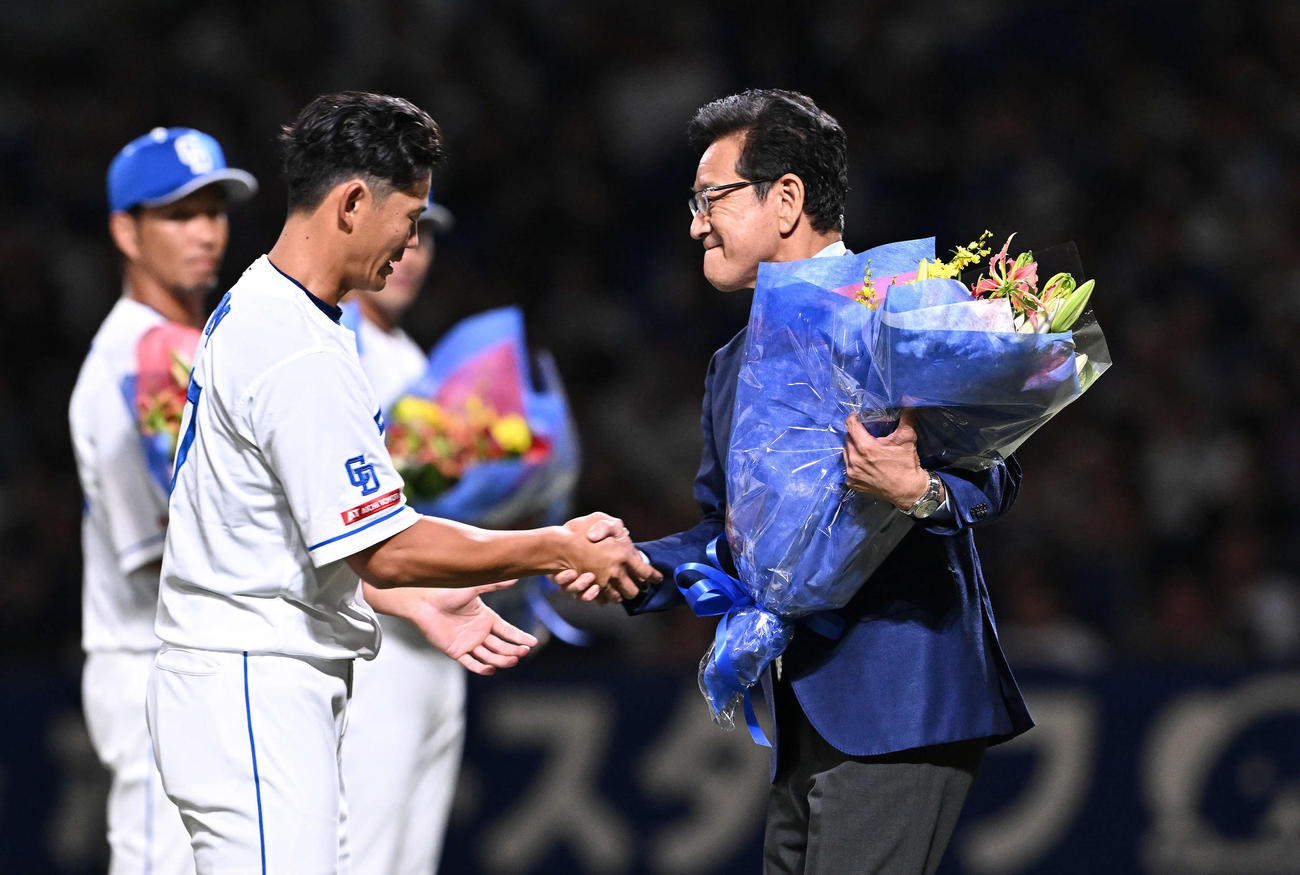 中日対巨人　引退セレモニーで中日大野奨（左手前）は花束を贈呈する栗山氏と握手を交わす（撮影・滝沢徹郎）