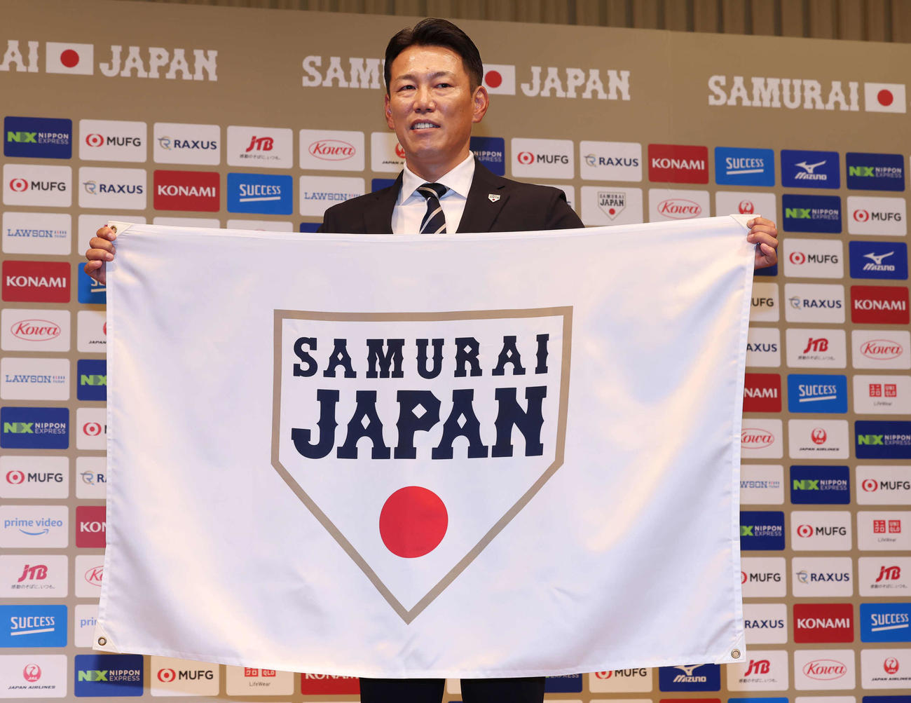 侍ジャパンのフラッグを手に写真に納まる井端新監督（撮影・丹羽敏通）