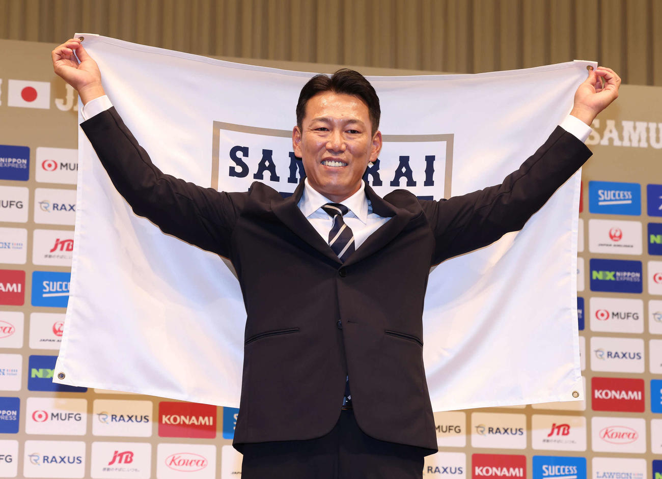 侍ジャパンのフラッグを手に写真に納まる井端新監督（撮影・丹羽敏通）