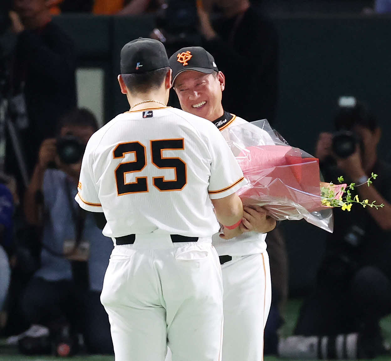 最終戦セレモニーで巨人岡本和（手前）からの花束に笑顔を見せる原監督（撮影・宮地輝）
