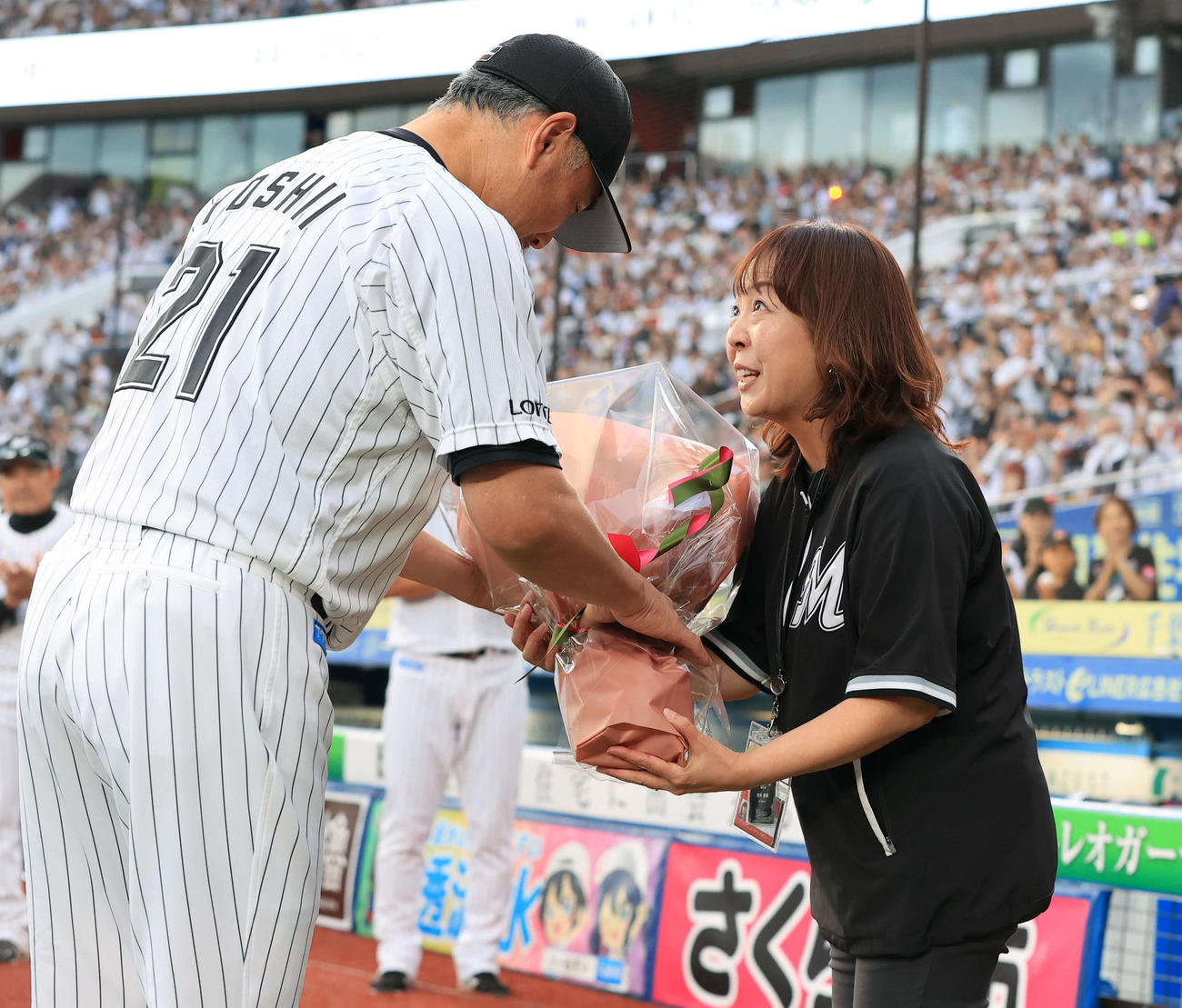 ロッテ対オリックス　今季限りで場内アナウンスから卒業する谷保恵美さん（右）は、ロッテ吉井監督から花束を贈られる（撮影・浅見桂子）